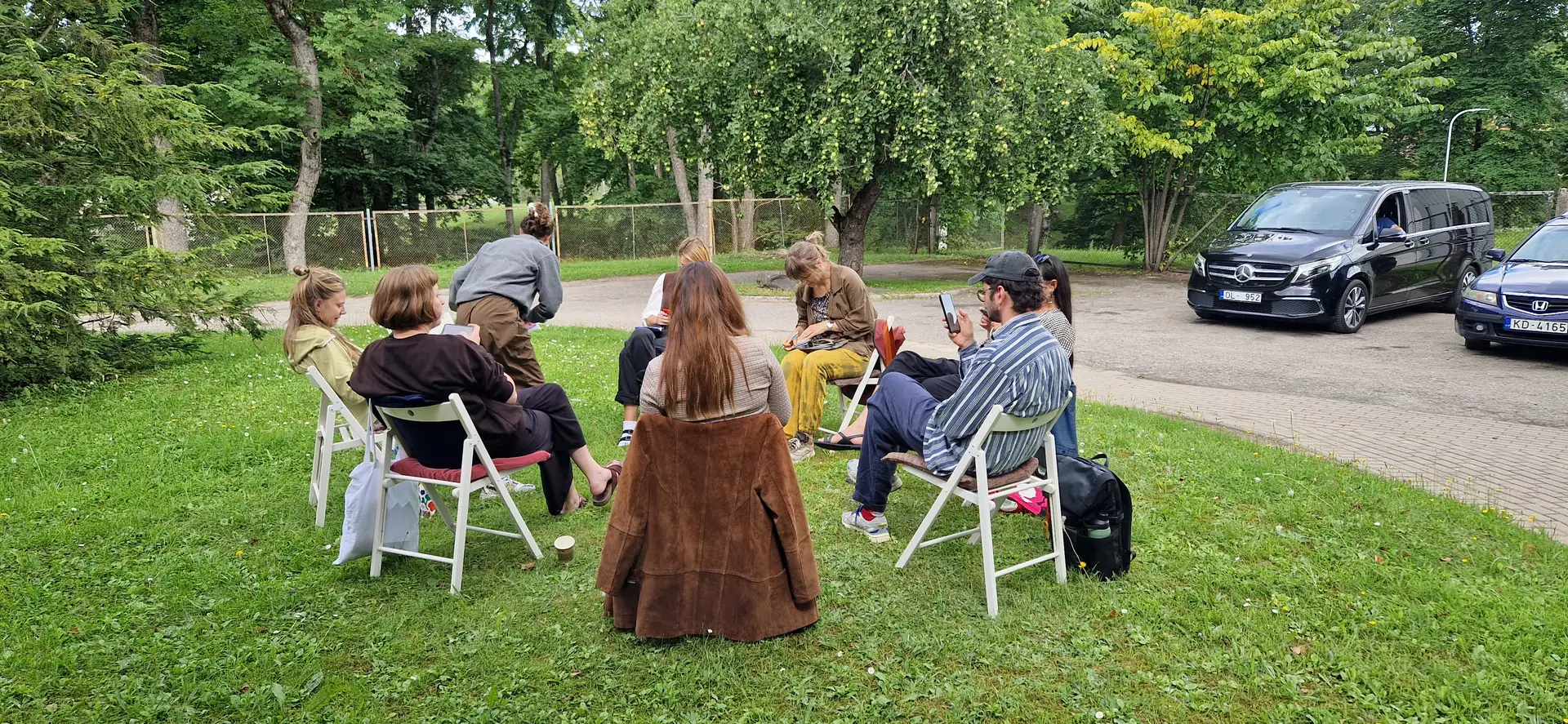 People sitting on chairs on a lawn, discussing